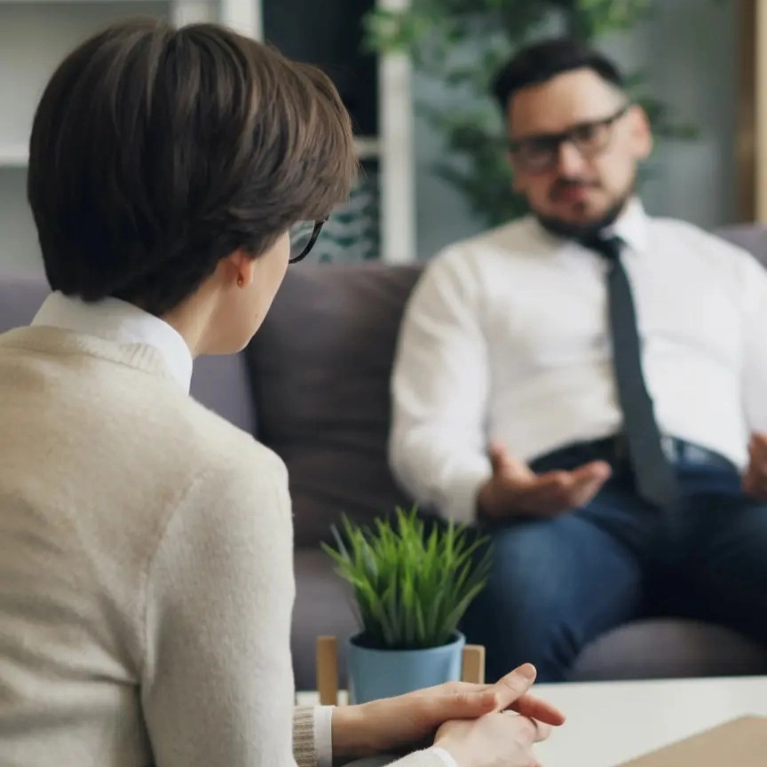 Firefly_Gemini Flash_A men talking with a white female therapist in a bright, cozy counselling room fille 744069 (2) Client and therapist talking during a counselling session